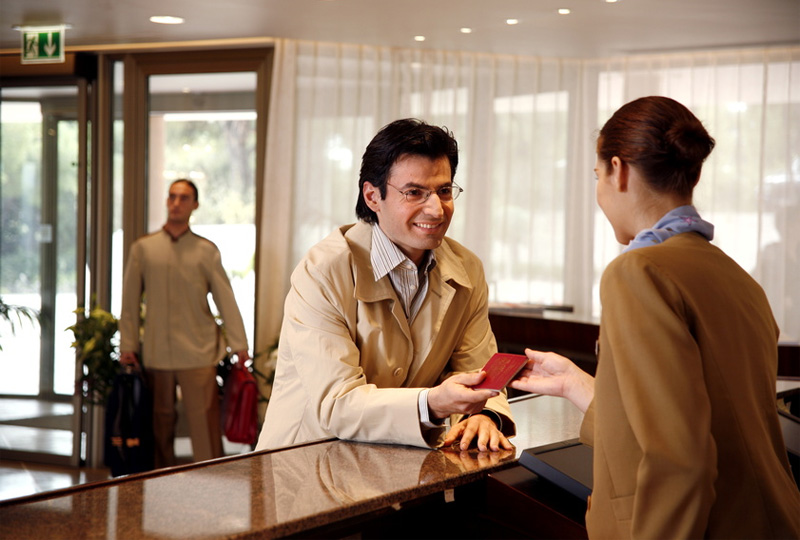 Szenisches Foto einer Hotellobby mit Pförtner sowie Empfangspersonal am Tresen